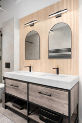 A modern bathroom with white oak wood slat paneling on the wall with arched mirrors, mounted...