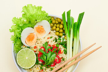 Beautiful Noodle Dish with Green Onions, Eggs, Green Pea, Red Hot Pepper, Greens and Lime on White Background. Instant Noodles with Vegetables - Top View