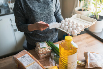 Woman checking receipt from supermarket during inflation with rise in price of food and consumer products