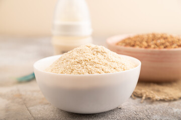 Powdered milk and buckwheat baby food mix, on brown concrete, side view, selective focus