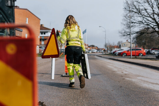Naklejki Female road worker carrying road sign