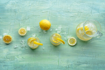 Lemonade. Lemon water drink with ice. Two glasses and a pitcher on a blue background, overhead flat...