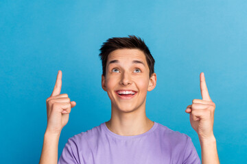 Handsome smiling man pointing away up follow adverts empty space on blue color background