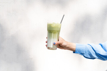 Female holding iced matcha latte . Summer refreshing beverage cold drink