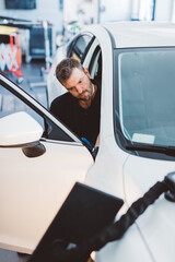 Naklejka premium Car mechanic working to remove dent in workshop.