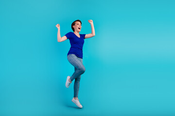 Fototapeta na wymiar Full length charming cheerful girl jumping rejoicing fists celebrate isolated blue turquoise color background
