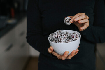 Woman's hands holding bowls with coconut balls