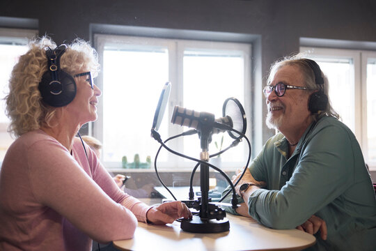 Mature man and woman talking together on radio show or podcast
