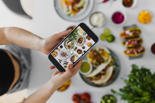Person photographing healthy feast with various Mexican foods