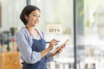 Startup successful small business owner sme beauty girl stand with tablet smartphone in coffee shop restaurant. Portrait of asian tan woman barista cafe owner. SME entrepreneur seller business concept