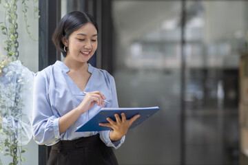 Boring young business Asian woman holding document file and looking at camera stand on a workplace office.