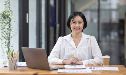 Asian Businesswoman Using laptop computer and working at office with calculator document on desk,...