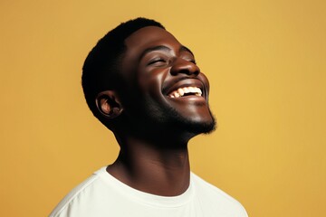 African-american model guy laughing without looking at the camera in a yellow background