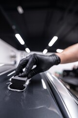 Man applies a ceramic coating or graphene ceramic coating to the paintwork of a silver car in a car...