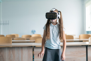 Caucasian schoolgirl wearing virtual reality glasses in the classroom. 