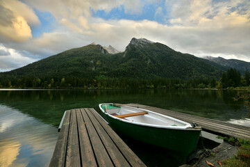Ein Ruderboot liegt in einer schönen Abendstimmung an um Bootsanleger eines Bergsee und im...