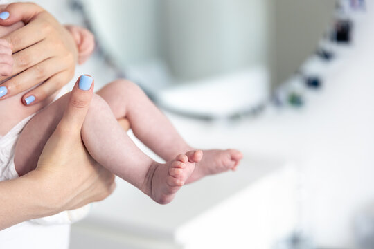 Newborn baby in mother's hands, legs close-up.