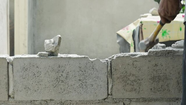 Hand of worker using hammer smashing and demolish on brick wall at construction site