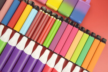 Set of multicolor disposable electronic cigarettes on a red background.