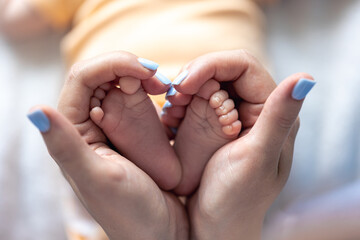 Mom holds the legs of a newborn baby in her hands.