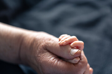 Hands of senior person and little baby close up.