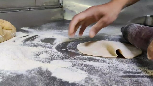 A close-up of an Indian chef skillfully preparing fresh chapatis on a gas stove.