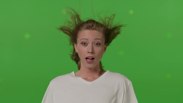 Caucasian girl in front of TV screen getting blown away. Cinema concept with chroma key.