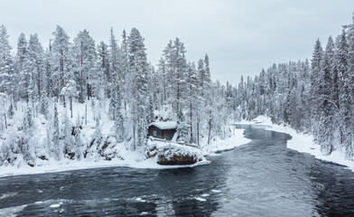 Winter in Finland; landscape in Oulanka National Park with the Kitkajoki river and snow covered...