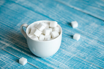 Cup with sugar cubes on a wooden surface, close-up.