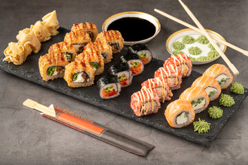Sushi set of various products on a black stone plate. Blur background and selective focus