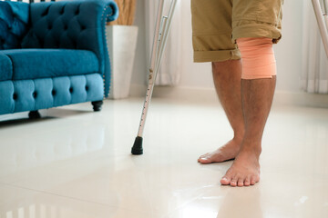 Man with knee injury had bandaged his knees and was using crutches learning to walk in the room.