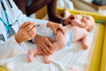 Close up of pediatrician vaccinating baby at doctor's office.