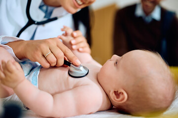 Close up of doctor examining baby with stethoscope at clinic.