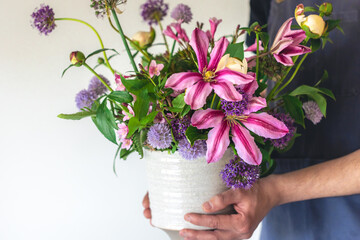 A man in an apron holds a vase of flowers, close-up.