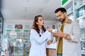 Young pharmacist advising her customer in buying medicine in pharmacy.