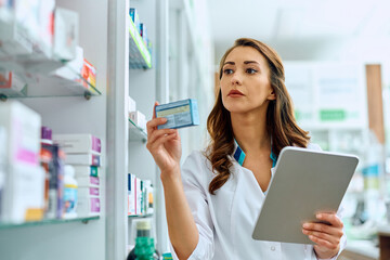 Female pharmacist using digital tablet while going through inventory in pharmacy.