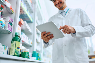 Close up of pharmacist working on digital tablet in drugstore.