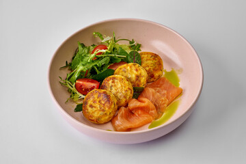 Ukrainian salty syrnyky with lightly salted salmon and sun-dried tomatoes served with mixed salad. Cheese pancake