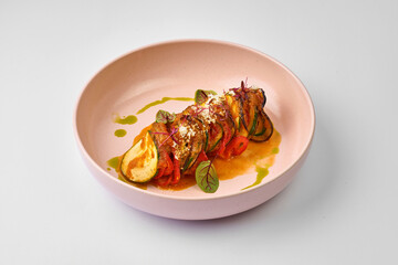 Vegetable ratatouille with sauce in a plate on a gray background