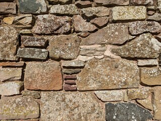 A close up view of a textured and ancient stone wall at Melrose Abbey in the Scottish Borders, UK.