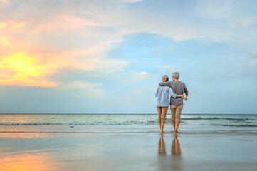 Plan life insurance of happy retirement concepts. Senior couple walking on the beach holding hands at beach sunrise in evening. - obrazy, fototapety, plakaty