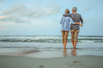 Plan life insurance of happy retirement concepts. Senior couple walking on the beach holding hands...