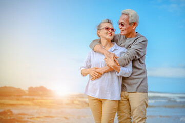 Fototapeta na wymiar Plan life insurance of happy retirement concepts. Portrait of Senior couple embrace on the beach sunset in evening.