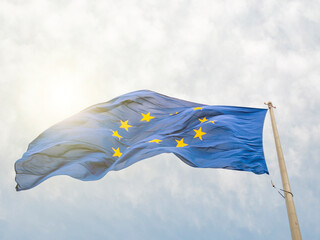 European Union EU flag waving in front of European Parliament building. Brussels, Belgium, isolated on blue sky with sun