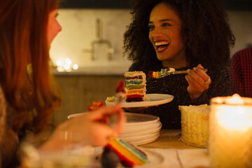 Laughing friends enjoying cake at candlelight table