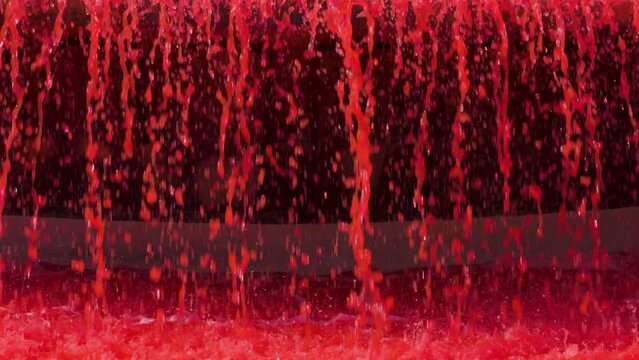 Bloody red color water splashing in slow motion on a rippled surface. Halloween blood concept. Decorative colored liquid in the fountain