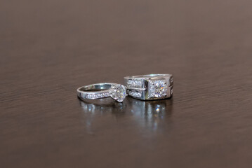 Wedding rings on a dark brown wood grain background. A couple's diamond ring against a wooden background.