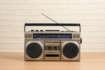 portable radio receiver tape cassette recorder on wooden table in front of white brick wall