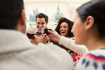 Enthusiastic friends toasting wine glasses at Christmas dinner