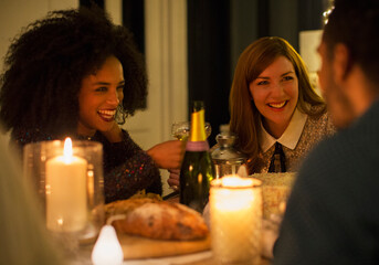 Smiling friends drinking champagne at candlelight dinner table